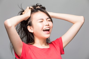 Frustrated and stressed angry Chinese woman pulling her hair with hands